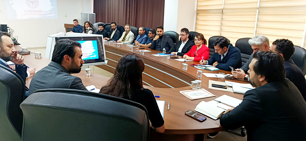 [Fotoğraf: Toplantı masasındaki yetkililer ve Dr. Muhammed Tosun’un konuşma anı]