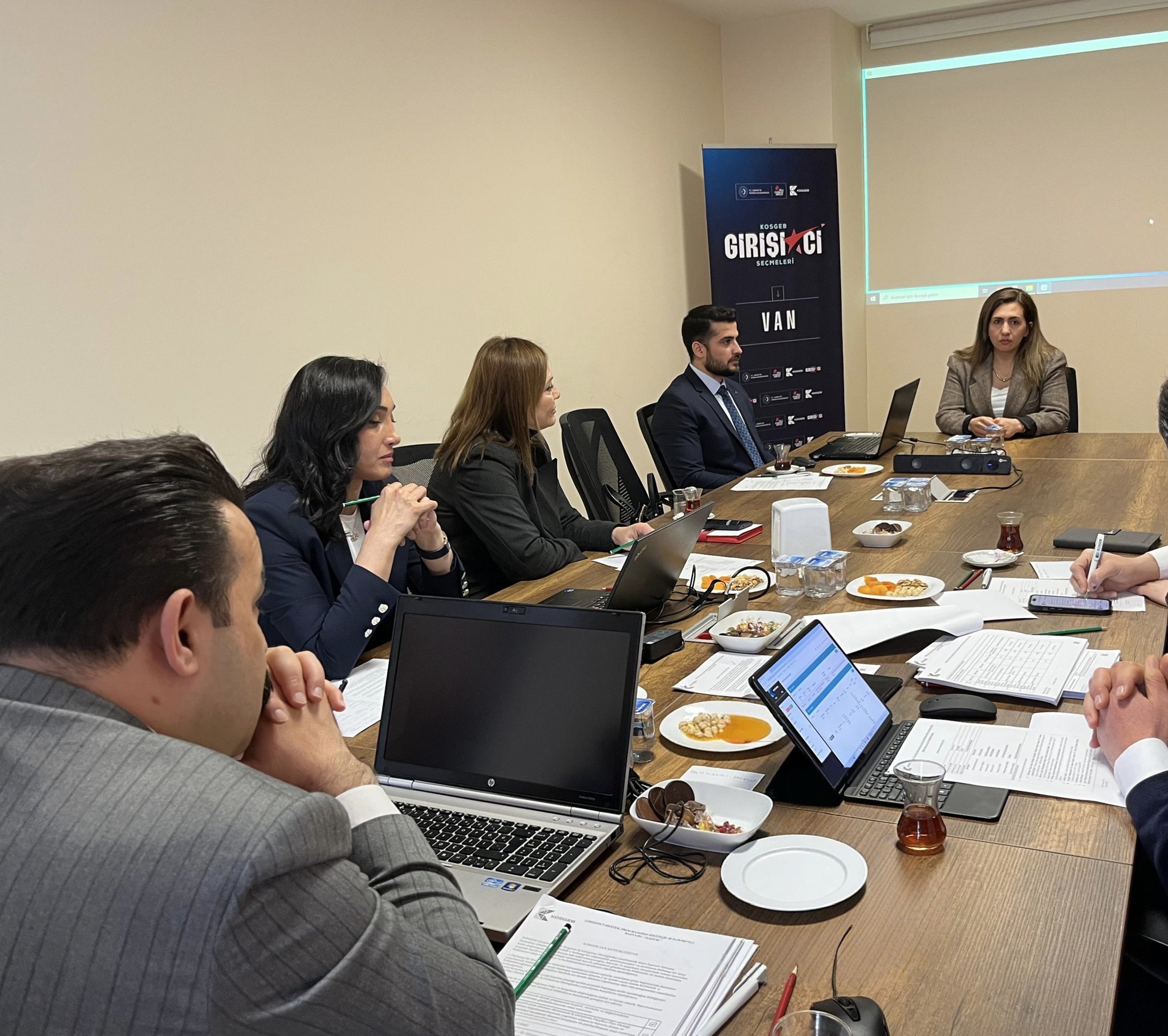 [Fotoğraf: Toplantı masasındaki yetkililer ve projelerin incelenme anı]